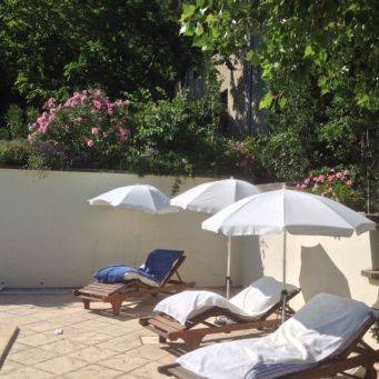 Buitenruimte met vier houten ligstoelen en witte parasols bij Le Mas d’Aunas in Zuid Ardèche, Ligstoelen