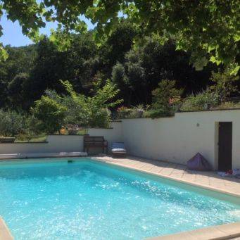 Rustig buitenzwembad met helder blauw water, betegeld terras en groene heuvels, ontspanning bij zwembad in zuid-ardeche