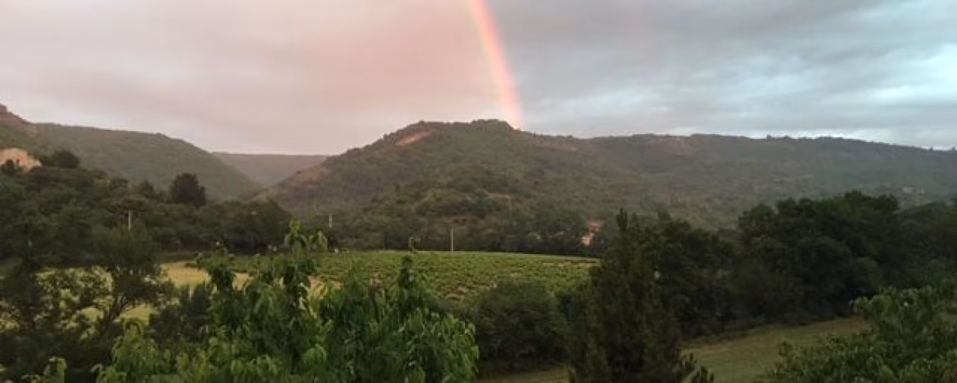 Prachtig natuurlijk landschapsbeeld met groene heuvels en een regenboog onder een bewolkte lucht, Le Mas d'Aunas rust